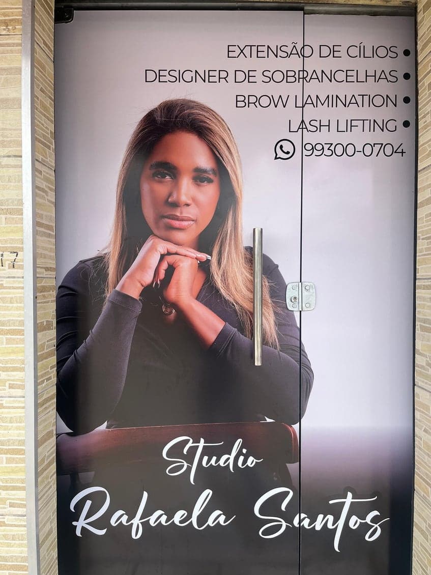 Fachada do Studio Rafaela Santos com a porta adesivada com a foto da Rafaela e a lista de serviços